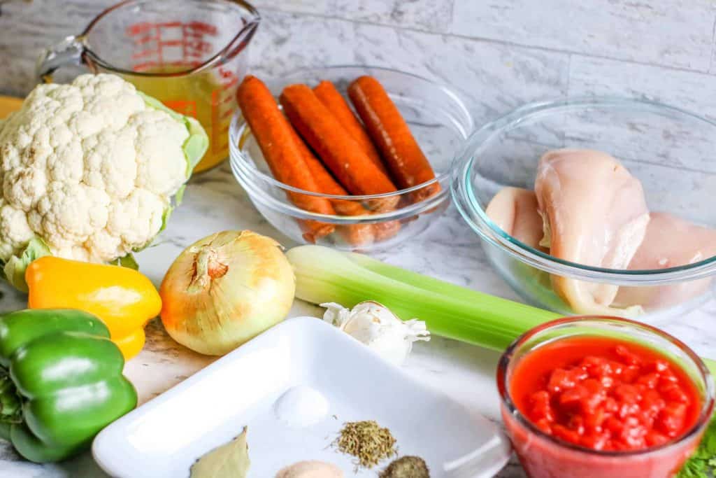 Vegetables and seasoning for jambalaya recipe on a marble background.