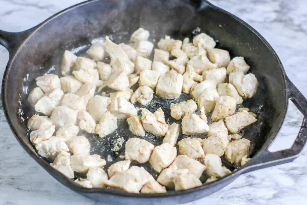 Chicken breast in a black iron skillet.