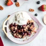 Blueberry strawberry dump cake served in a dish with vanilla ice cream on top