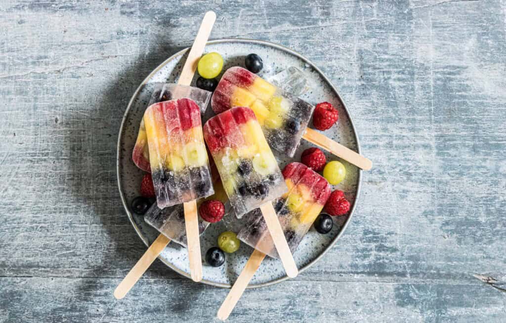 Rainbow Fruit Popsicles on a gray plate.