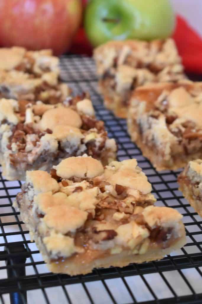 Caramel Apple Bars on wire rack with apples in the background.