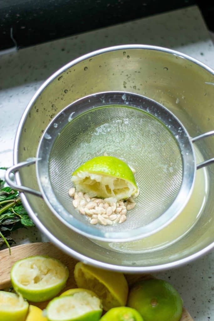 ½ lime in strainer after being juiced into stainless steel bowl.