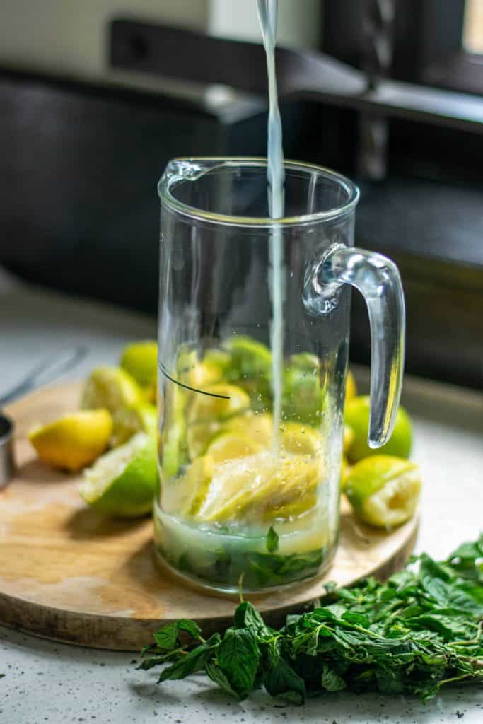Lemon juice being poured into a glass pitcher.