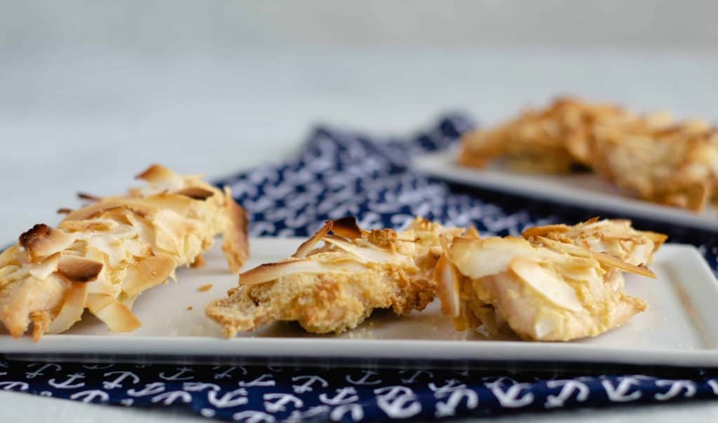 Head on shot of Keto Chicken Tenders on white plate on top of navy blue cloth napkin with anchors on the napkin.