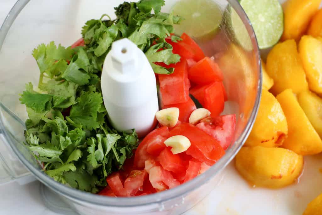 Cilantro and tomatos in a food processor.