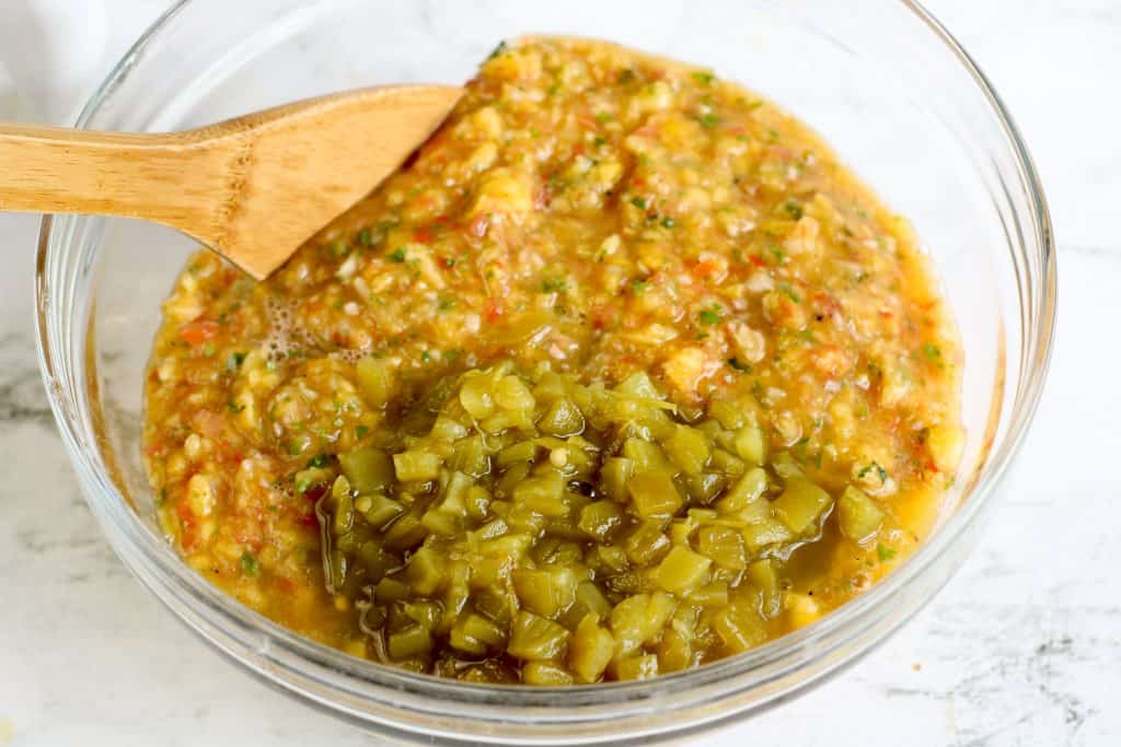 peach salsa in a bowl with green chiles on top.