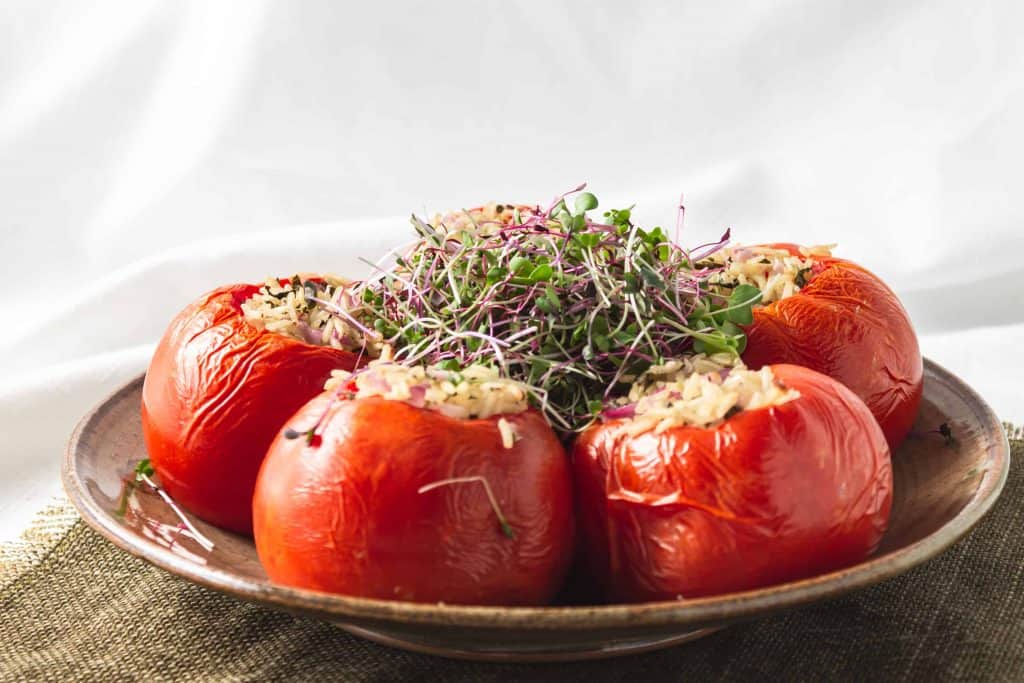 Rice stuffed tomatoes with micro greens on top.