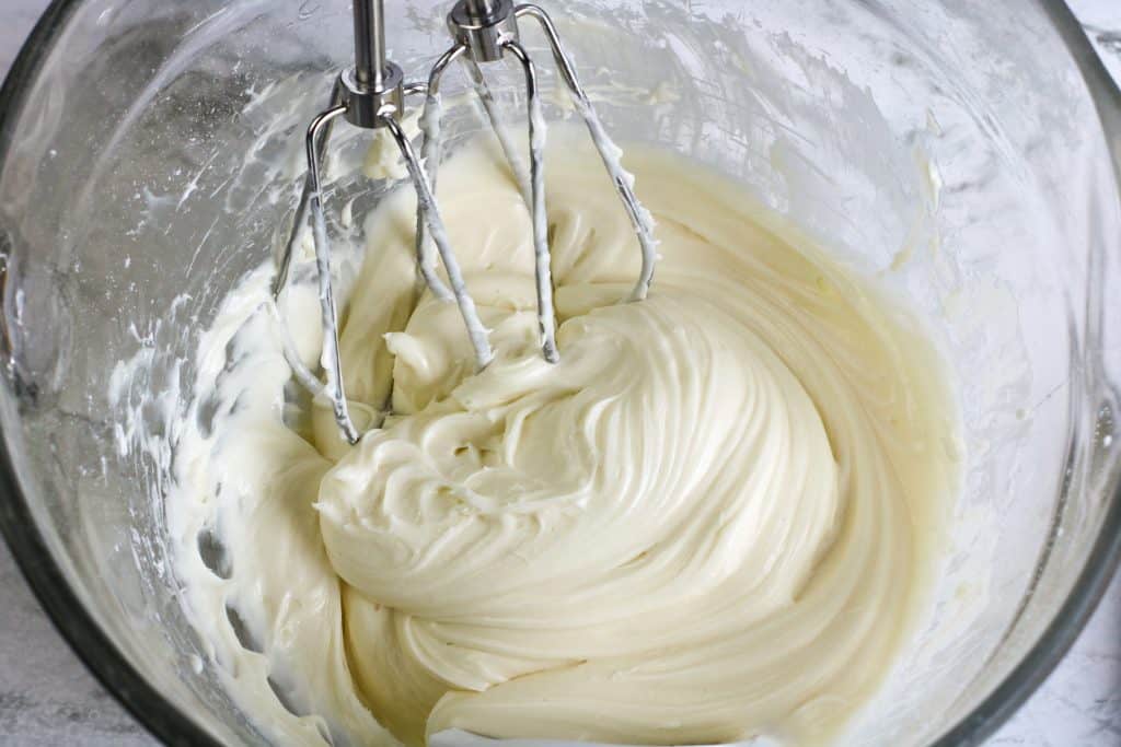 Cream cheese icing being made with electric mixer.