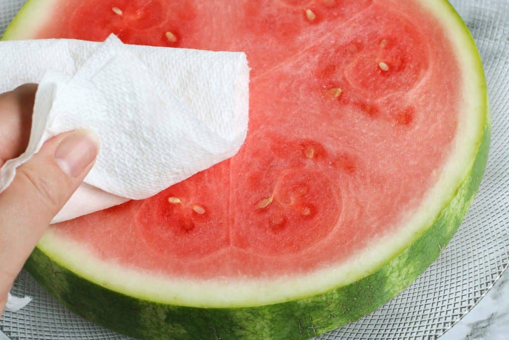 wiping a piece of watemelon with paper towel.