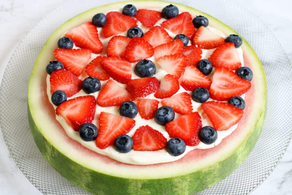 Watermelon slice with cream cheese frosting, strawberries and blueberries.