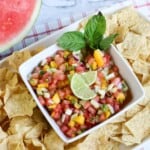 Watermelon salsa in a white square dish with chips around it and a slice of watermelon on the side.