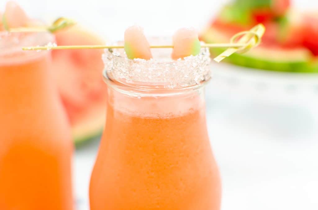 Closeup of watermelon slush with salt rim and toothpick with sour patch watermelon garnish.