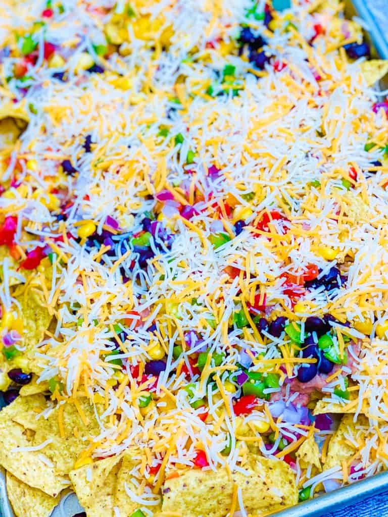 Closeup of shredded cheese on top of loaded vegetarian nachos.