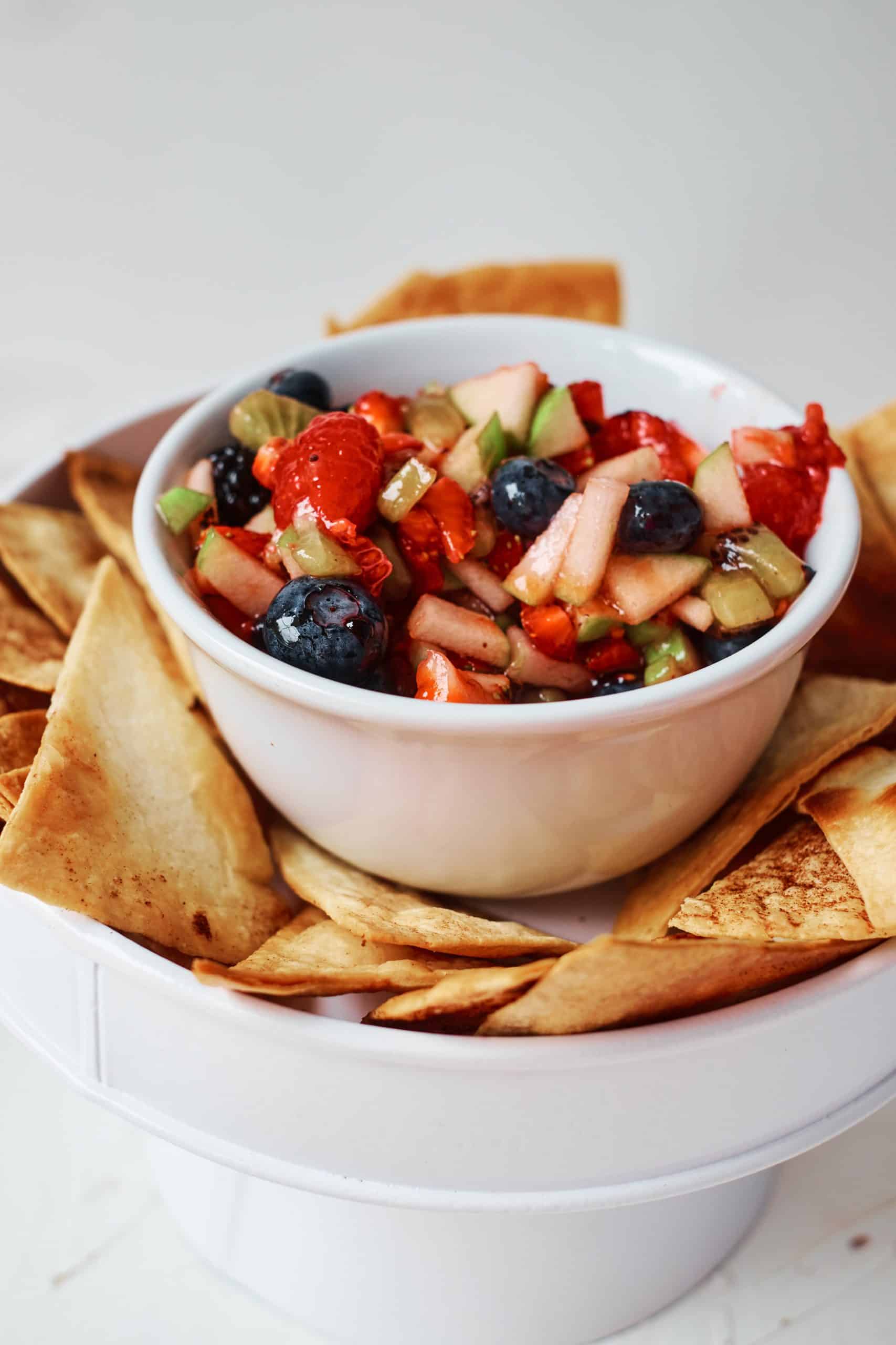 Fruit Salsa in a white bowl surrounded by homemade cinnamon tortilla chips.