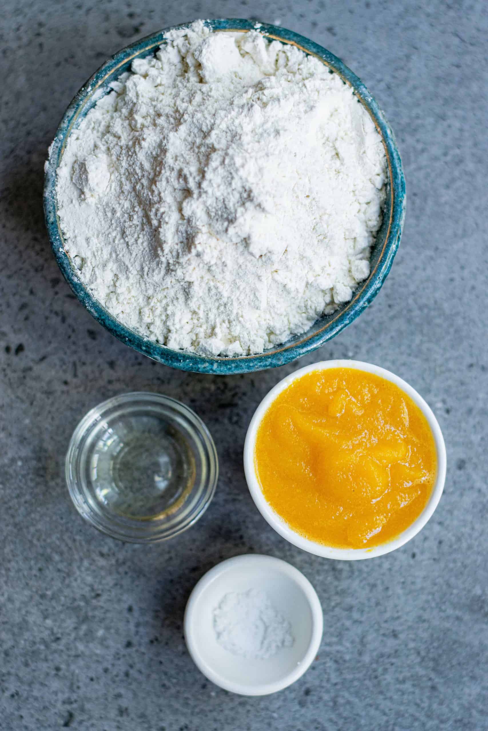 Flour, Pumpkin Purée, Sunflower Oil and salt on a marble counter top.