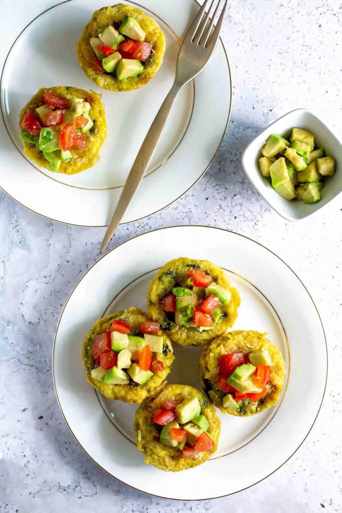 Overhead photo of keto egg cups on white plates on a white marble background.