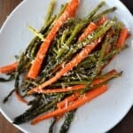 Carrots and asparagus with Parmesan cheese on a white plate.