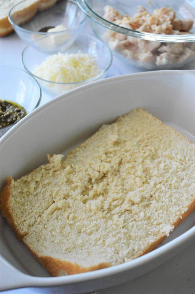 Sliced Buns in the bottom of a white ceramic oval dish with other ingredients in glass bowls in the background.