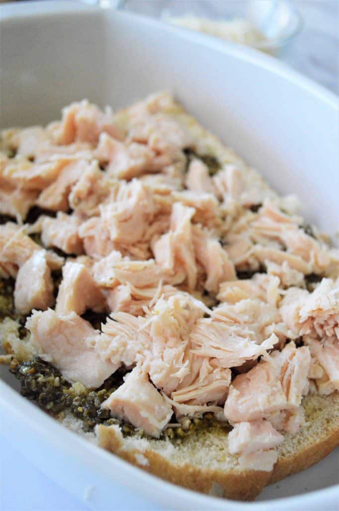 Shredded chicken on top of Pesto on buns.