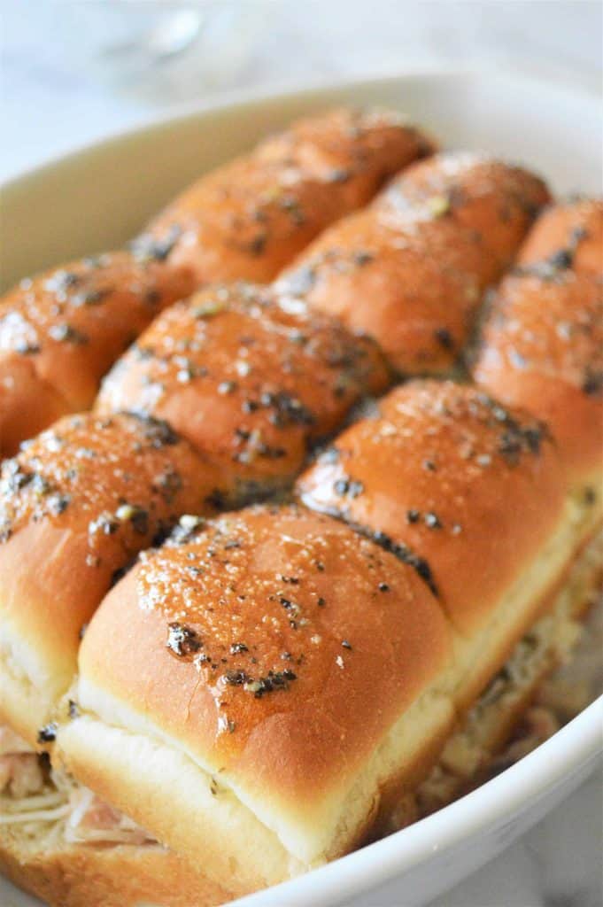 Closeup of sliders with butter herb sauce on top.