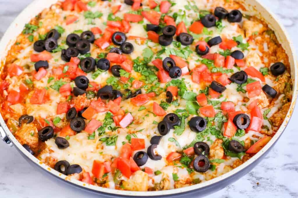 Tex Mex Chicken with Cauliflower Rice in a saut&eacute; pan, topped with black olives and cilantro.