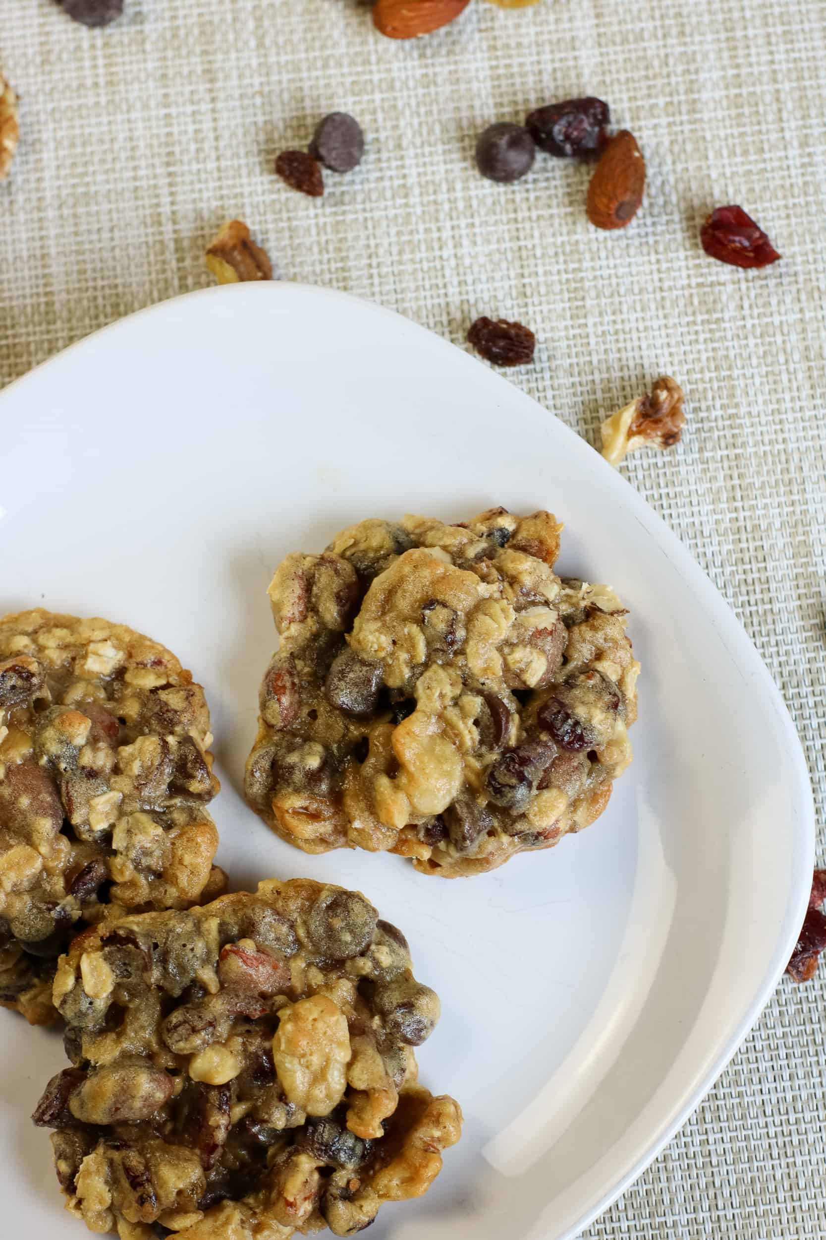 Trail Mix Cookies on a white plate with trail mix sprinkled around it.