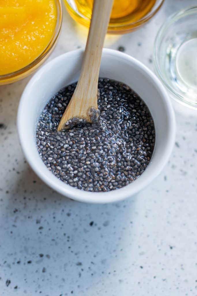 Chia eggs in a white bowl with a wooden spoon.