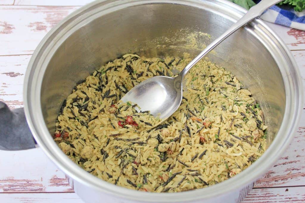 Wild rice in saucepan with a spoon it.
