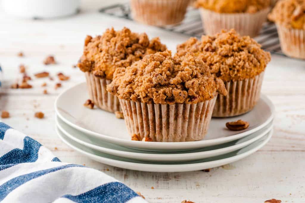 Whole Wheat Pumpkin Muffins stacked on white plates.