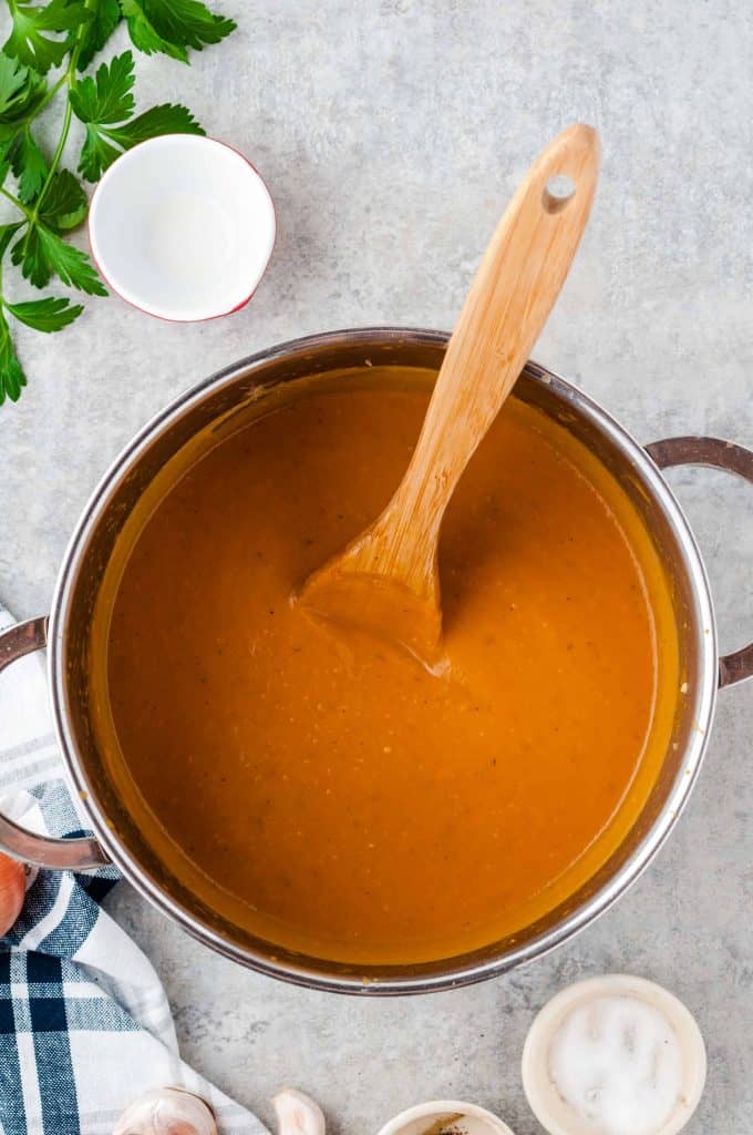 Easy to make pumpkin soup in a pot with wooden spoon.