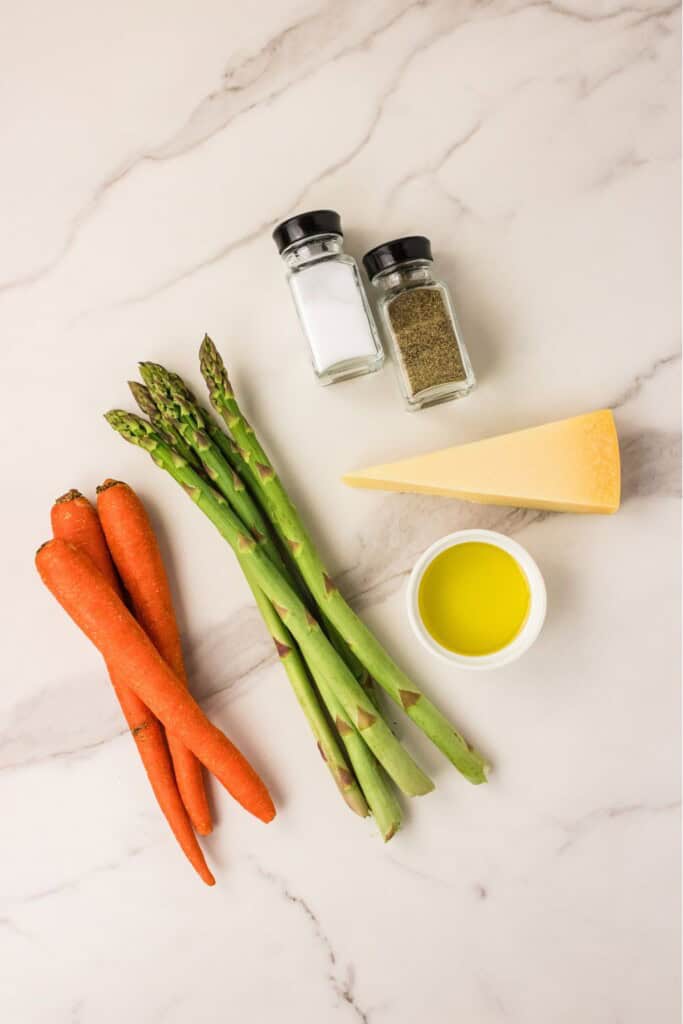 Fresh ingredients for roasted carrots and asparagus with Parmesan: whole carrots, asparagus, Parmesan wedge, olive oil, salt and pepper.
