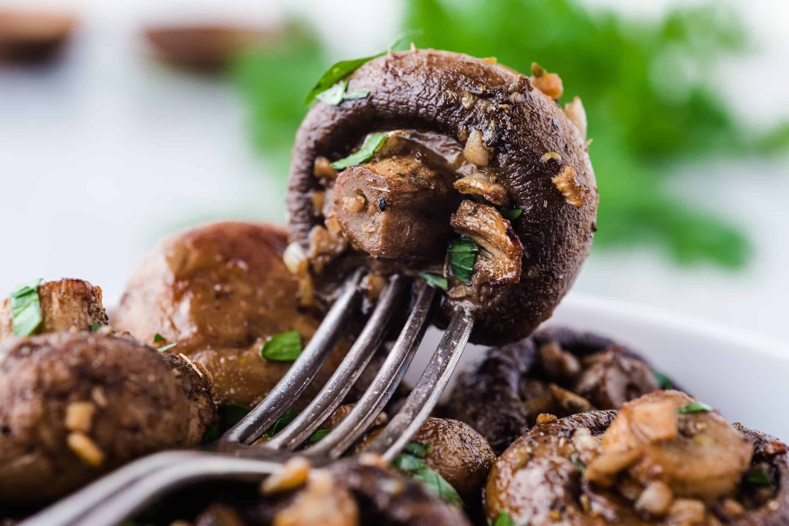 close up of roasted mushroom on a fork.