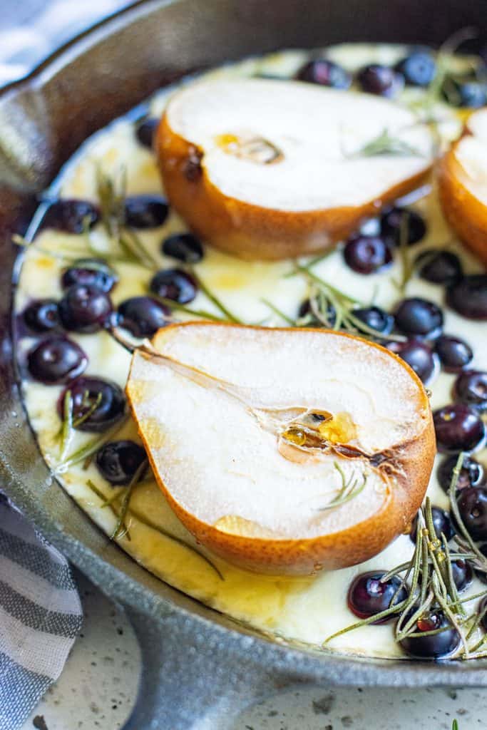 Closeup of pears, mozzarella , blueberries and rosemary in a black iron skillet.