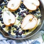 Pears, blueberries, mozzarella cheese and rosemary in a black iron skillet.