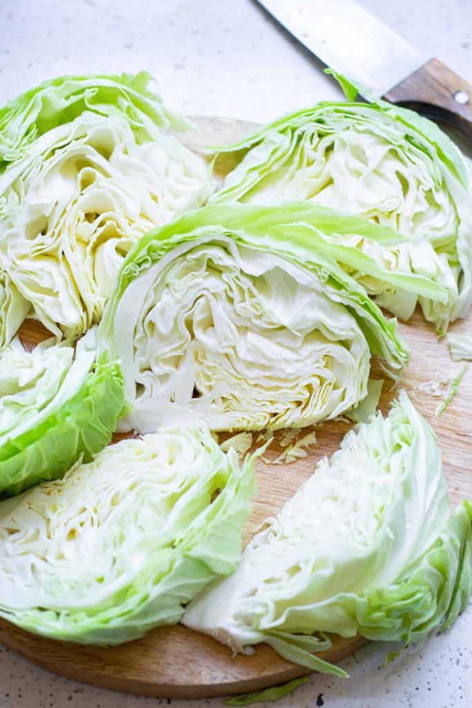 Sliced cabbage on a cutting board with a chef's knife on the side.