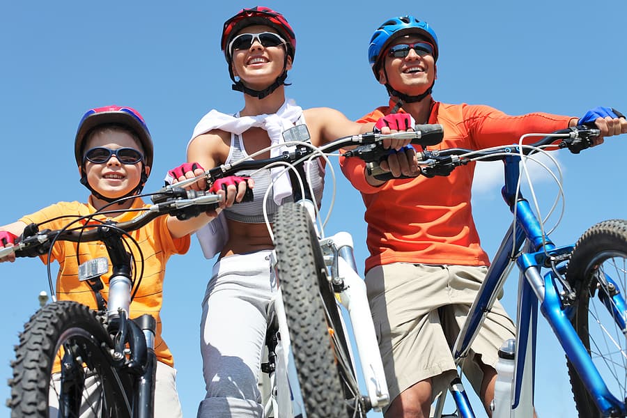 Portrait of happy family on bicycles against blue sky