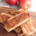 Apple Pie Egg Rolls on a wooden cutting board.