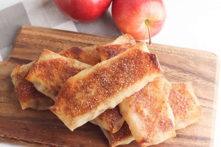 Apple Pie Egg Rolls on a wooden cutting board.