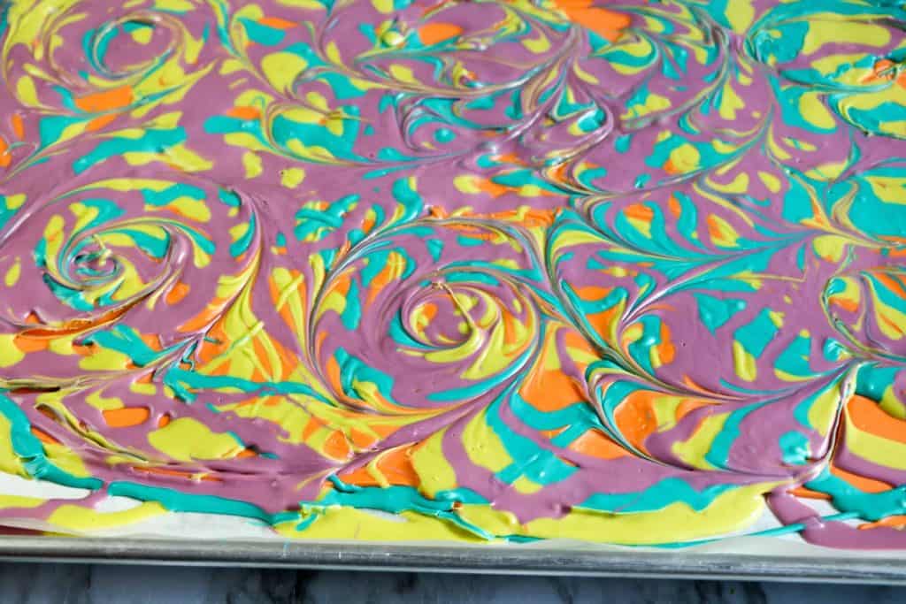 Colored candy melts spread on a baking sheet. 