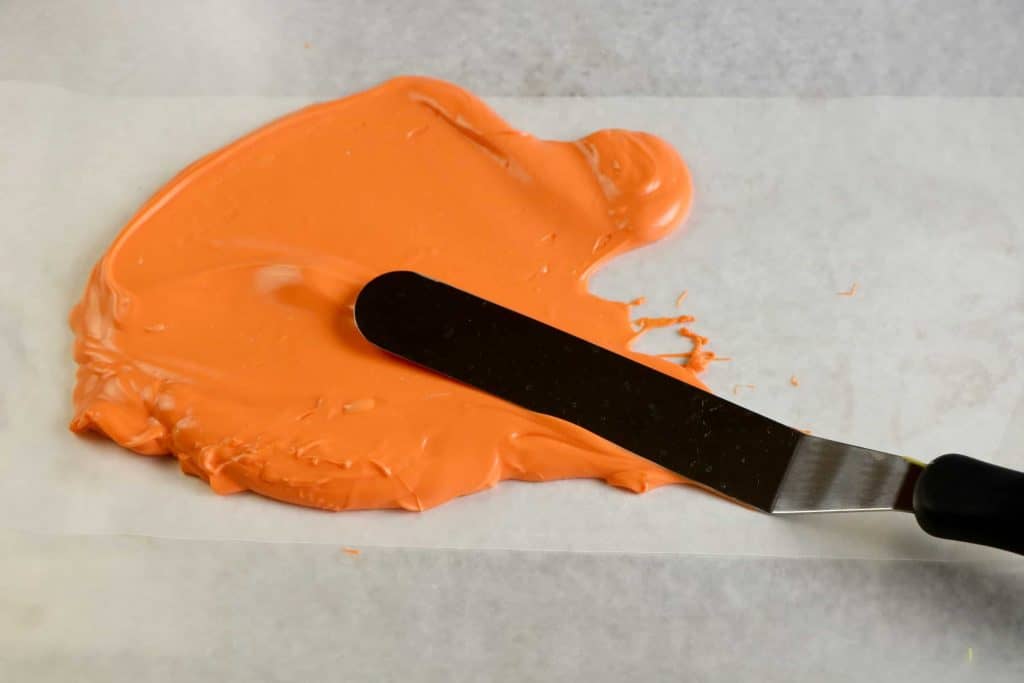 Spreading orange candy melts on waxed paper.
