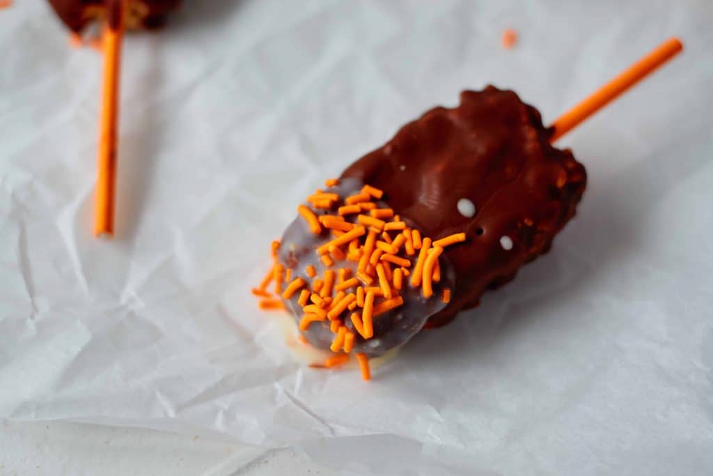 Closeup of chocolate pop with orange sprinkles.