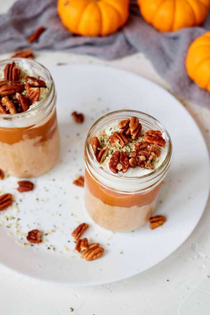 Pumpkin Pie Oats in a mason jar on a white plate.