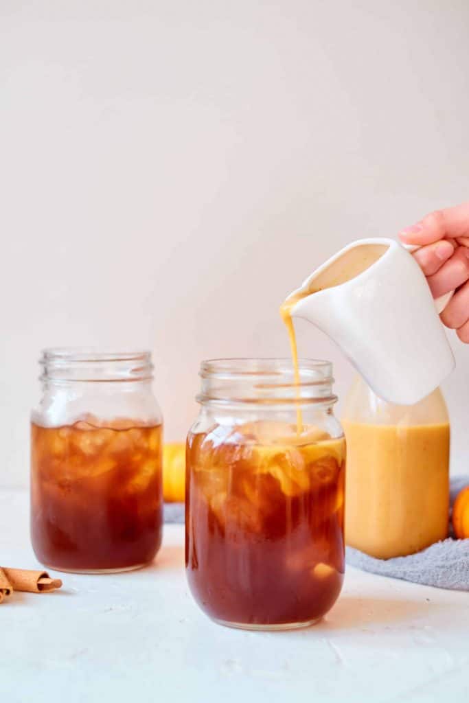 Adding pumpkin spice creamer to iced coffee.