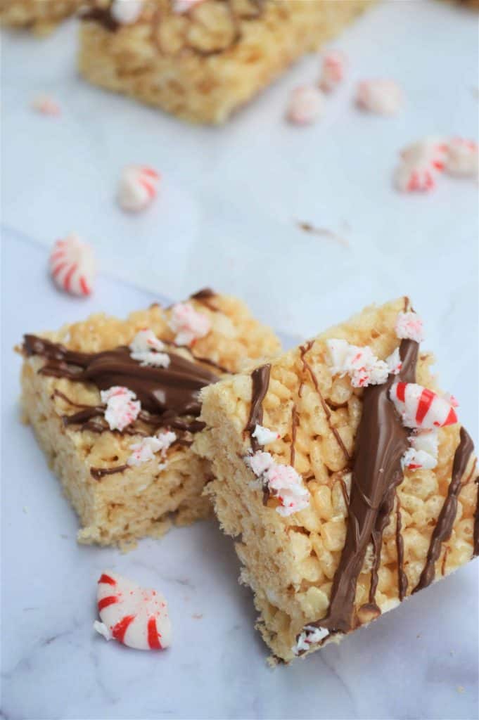 Two Rice Krispie treats with drizzled chocolate and crushed peppermint candies.