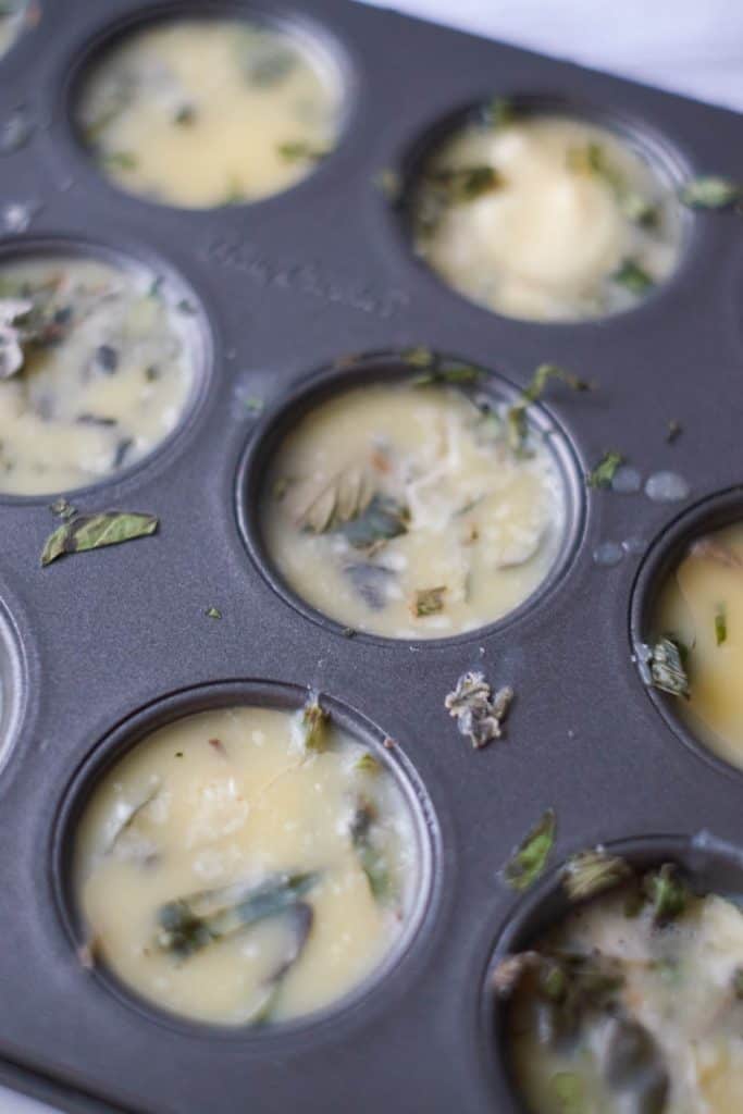 Italian Herbs in Melted Butter in a mini muffin tin.