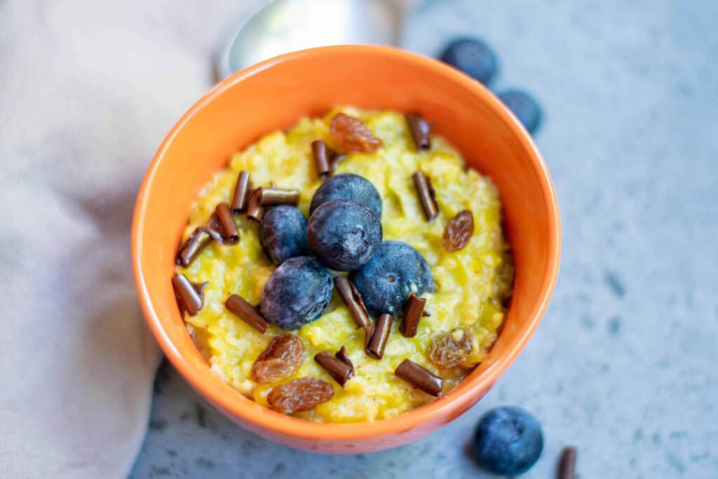 Vegan Homemade Pumpkin Oatmeal with blueberries in an orange bowl.