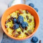 Vegan Homemade Pumpkin Oatmeal with blueberries in an orange bowl.