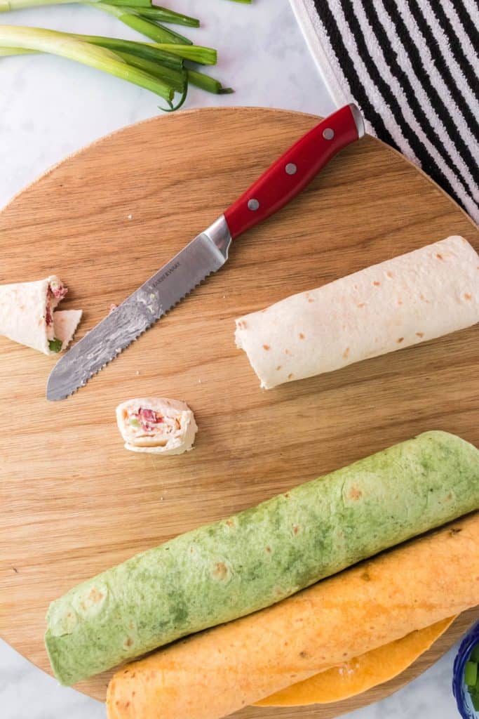 Cutting rolled up tortillas on a wood cutting board