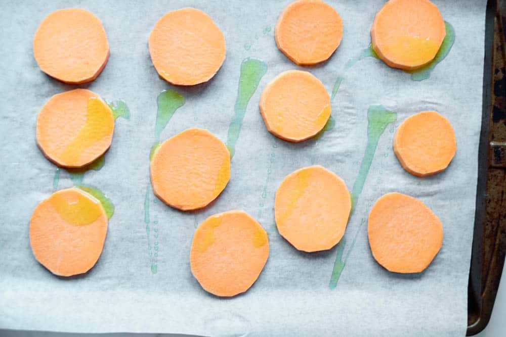 Sliced Sweet Potatoes on a baking sheet lined with parchment paper.