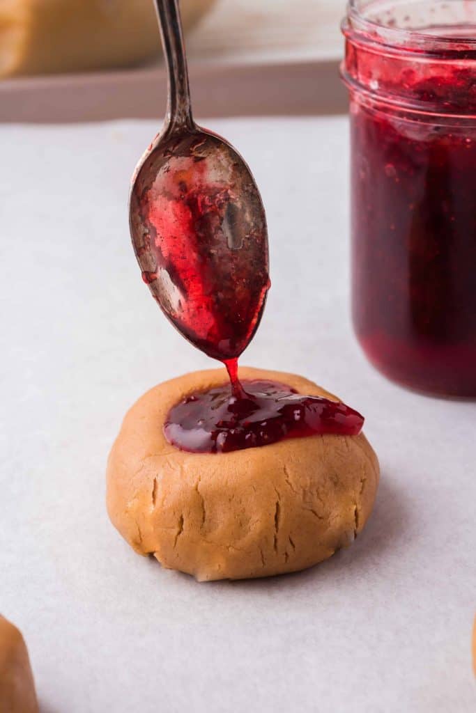 Strawberry jam being added to cookie